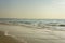 Yellow sandy beach against the backdrop of the foam of the ocean waves under a clear sky