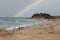 Yellow sandy beach, shoreline. Blue water and rainbow