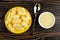 Yellow saucer with corn sticks, spoon, bowl with condensed milk on table. Top view