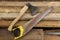 The yellow saw and axe lies on lumber.  Construction and repair.