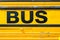 Yellow school bus..Fragment of yellow steel car bodywork, vehicle black text paint coating texture, selective focus, abstract