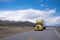 Yellow semi truck with trailer on road with snowy mountain