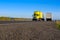 Yellow semi truck yellow trailer on road with asphalt rocks