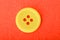 Yellow sewing button isolated on a red background