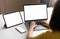 Yellow shirt woman using laptop and tablet, phone placed on the table, mock up of blank screen.