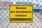 Yellow sign on fence saying: Entering the property prohibited. Parents are responsible for their children german: Betreten des