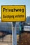 Yellow sign with German text `Private road no trespassing`. Private property.