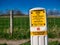 A yellow sign warning of a high pressure gas pipeline across fields in a rural area