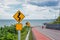 Yellow sign with winding road symbol in the countryside sea and sky background