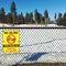 Yellow sign on wire fence with snowy ground and grass in park. Turn engine off. Improve air quality.