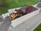 Yellow skid steer loader grabbing waste with scrap grapple, aerial view