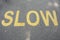 Yellow `slow` painted on the asphalt or road