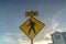 Yellow Slow sign and pedestrian crossing sign against cloudy sky at sunset