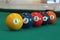 Yellow snooker ball with number one on it with other colorful balls placed in a row on a table