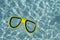 A yellow snorkel swimming goggles floating in a clear blue rippled swimming pool