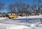 Yellow snow plow truck clearing snow in residential area.