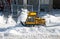 Yellow snowplough removing snow in the city