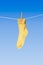 Yellow sock with wooden clothes peg on washing line against blue background