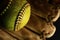 Yellow softball closeup with red seams on a brown leather glove.