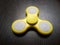 Yellow spinner toy at dark wooden board