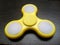 Yellow spinner toy at dark wooden board