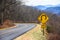 Yellow Spiral Curve Sign Along a Mountain Roadway