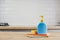 Yellow sponge and blue plastic bottle with liquid soap on wooden table with color cloths, kitchen background