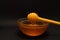 Yellow spoon of honey dipped in a jar of honey on a black background. Honey dripping around, nice and inviting photos