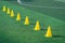 Yellow sport cones marker on soccer green grass pitch for children football training session