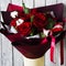 Yellow stand with burgundy bouquet of red roses green branches of a christmas tree with white flowers with pink ribbons on a gray