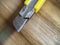 Yellow stationery knife with a blade on wooden background