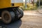 Yellow steamroller or soil compactor working on asphalt road at construction site