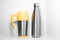 Yellow steel thermo mug and eco stainless thermal bottle sprayed with water on white background.