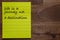 Yellow sticker with lines on a dark wooden background with the handwriting of the wisdom of life by Ralph Waldo Emerson: Life is a