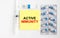 Yellow sticker with text Active Immunity on a white background with syringes, pills and ampoule