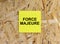 Yellow Sticker with text Force Majeure on the wooden background