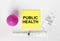 Yellow sticker with text Public Health on a white background with syringes, enema and ampoule