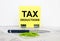 Yellow sticker with text Tax Deductions stands on office clips. Next to it is a blue pen with green paper clips