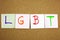 A yellow sticky note post it writing, caption, inscription LGTB Lesbian, gay, bisexual and transgender acronym in black ext on a s