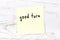 Yellow sticky note on wooden wall with handwritten word good turn