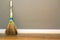 Yellow straw broom leaning to empty room wall