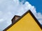 yellow stucco house elevation detail. gable end. brown stained wood trim. brick chimney
