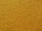 Yellow stucco texture on exterior wall with fine grains