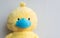 Yellow stuffed toy duck wearing a blue face mask