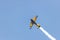 Yellow stunt plane climbing trailing a smoke contrail