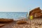 Yellow suitcase, surfboard and hat on sand. Sea view and rocky coastline. Summer time and holiday trip idea, copy space