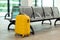 Yellow suitcase in the waiting room. Vacation and travel. Copy space. Concept waiting for the plane