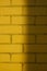 Yellow sunny brick wall texture background. Half shaded beautiful new bricks