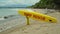 Yellow surfboard on beach with red text surf rescue emergency on a beach