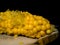 Yellow sweet corn half-eaten. Black background. Close-up picture